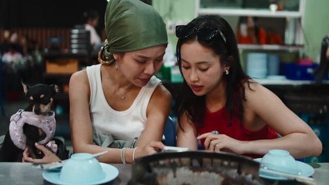 Two asian friends having dinner at a thai bbq restaurant