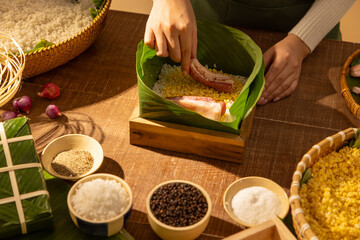 Hands arranging dong leaves and rice layers to wrap Chung cake, symbolizing Vietnamese Tet traditions and ancestral cooking rituals during Lunar New Year celebrations