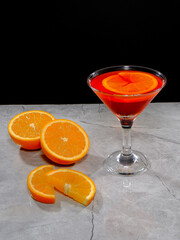Vibrant orange cocktail with fresh slices on a modern gray surface closeup view