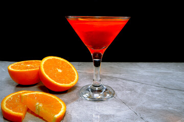 Vibrant orange cocktail with fresh slices on a modern gray surface closeup view