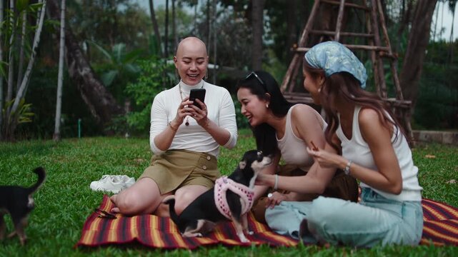 Group of friends using a smartphone with dogs in a park
