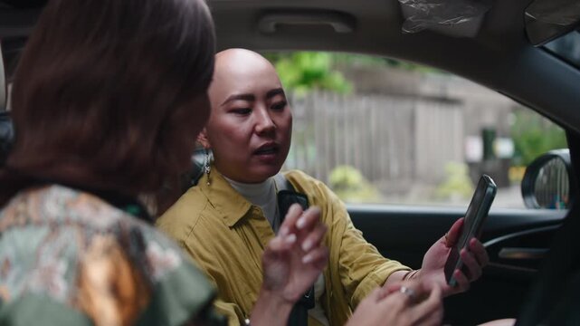 Asian friends discussing route using navigation app in car