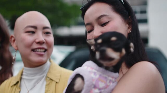 Asian woman cuddling chihuahua puppy with friend