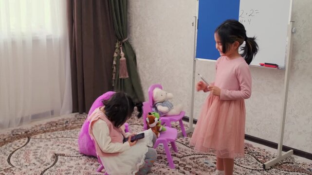 children engaging in imaginative play, two children in dresses act out roleplay in cozy home setting, two young girls with toys and whiteboard enjoying creative pretend play in warm living room