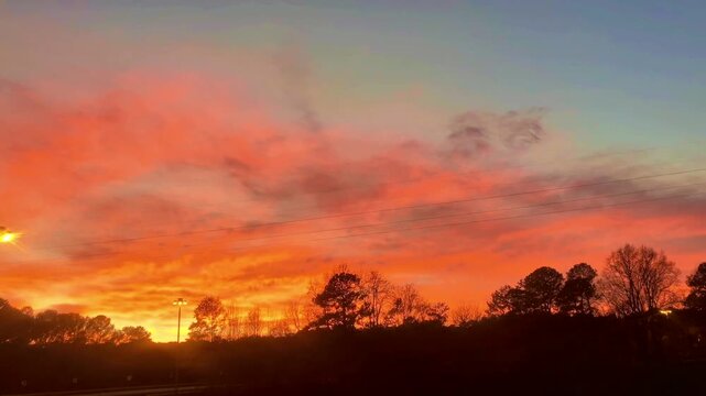 Beautiful Reddish Cloud Fiery Sunset Sky with Silhouetted Power Transmission Tower and Trees 