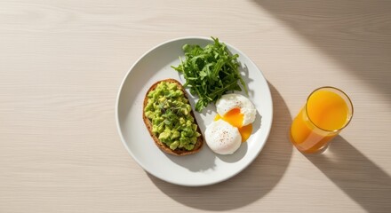 Bright morning breakfast with avocado toast, poached eggs, arugula, and orange juice on a white