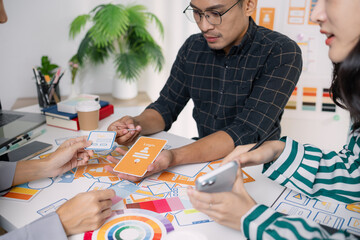A group of UX/UI designers brainstorming creative ideas together, discussing color palettes and layout concepts for a new mobile application interface in a modern design office.