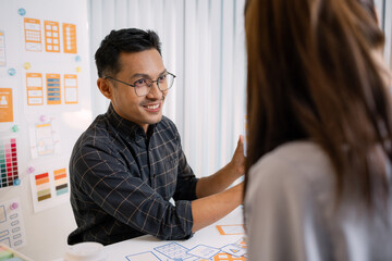 A group of UX/UI designers brainstorming creative ideas together, discussing color palettes and layout concepts for a new mobile application interface in a modern design office.