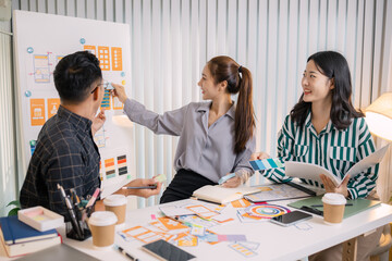 Designers having a UX/UI planning meeting to refine mobile app layouts and user flow. They collaborate closely to create functional and visually appealing interface solutions.