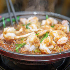 Woman tourist eating baked shrimp with glass noodles and garlic in restaurant. Popular foods for tourist eating in Chengdu, China. Chinese Asia and Sichuan foods concept