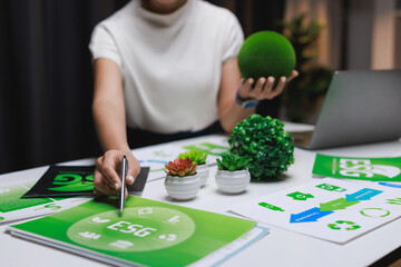 Fototapeta premium Woman analyzing esg report with green globe and plants