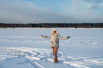 A happy woman on a river bank of a frozen river. Winter walking.
