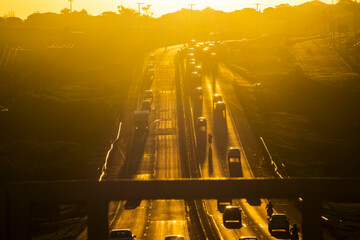 Marilia, SP, Brazil, November 19, 2025. Highway SP-294 in Marilia, at sunset. Intense traffic of cars and trucks flows through the green landscape, illuminated by the golden hour light.
