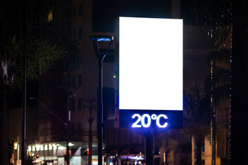 A digital street billboard at night displays the temperature of 20&deg;C. A large blank white screen provides copy space for advertising or public information mockups.