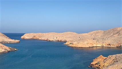 Serene Coastal Vista, Tranquil Bay With Rocky Islands, Peaceful Shoreline Featuring Clear Blue Skies And Limestone Cliffs, Calm Waters Surrounded By Rocky Isles Under Bright Sunlight And Open Horizon