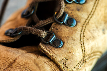 Close-up of a well-worn brown leather hiking boot. Detail of the textured material, sturdy laces, and metal eyelets, suggesting a story of adventure, travel, and durability.