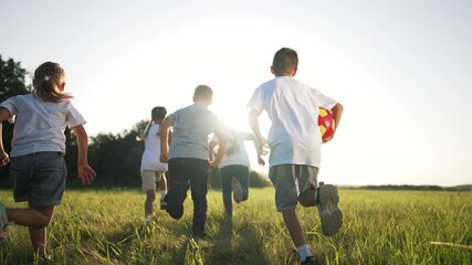 Children running with soccer ball across green grass field at sunset while child and kid and boy and girl play and run together showing teamwork play joy energy and motion under warm sunlight - Powered by Adobe