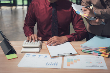 Focused Financial Discussion: A dynamic scene of financial experts deeply engrossed in a discussion, as one meticulously works a calculator while the other provides insights