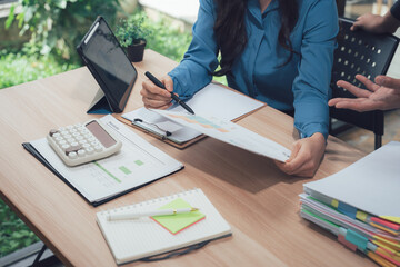 Analyzing Finance on Desk: Focused examination of a financial document, amidst office essentials,...