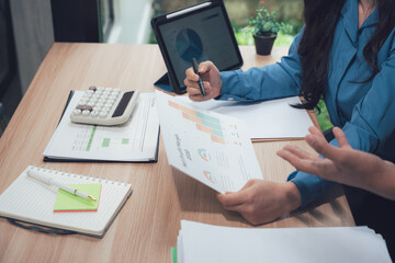 Financial Focus: Two colleagues diligently review financial reports, poring over charts and data to analyze performance and plan for future success. It’s a scene of strategic collaboration.