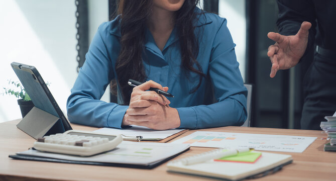 Focused Collaboration: A professional woman and man engage in a focused business discussion, their interaction suggesting a meeting about project strategy and brainstorming.