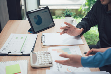 Business Discussion on the Desk: An interactive image that encapsulates the dynamics of collaboration and strategic planning with hands-on elements, charts and calculator.