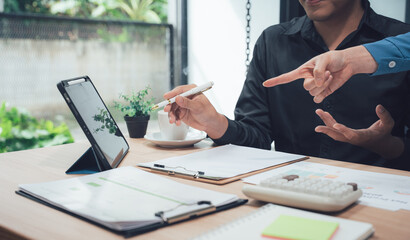 Workplace Collaboration: Two business professionals engage in a productive discussion, reviewing charts and reports. A tablet sits on the table, likely displaying important data.