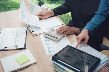 Analyzing Data: Hands of individuals meticulously examine vital financial data and figures, working to extract insights. This depicts a strategic environment.