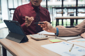 Analyzing Agreement: A focused business meeting captures the essence of a deal, as a hand extends a pen and a tablet rests, while agreements and financial insights await resolution