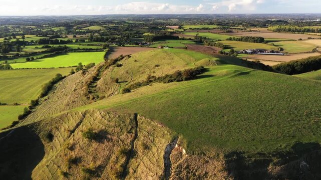 Cley Hill Camp univallate Iron Age hillfort near Warminster, Wiltshire. The 2 central Bronze Age bowl barrows seen from the south. Video fly in up from old quarry to barrows