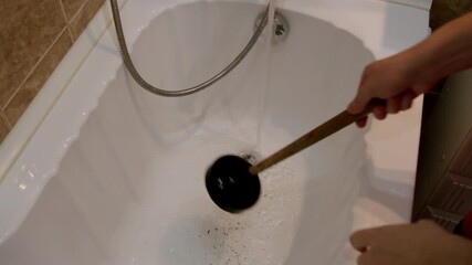 Individual using a black plunger to clear a clogged bathtub drain, demonstrating the action of plunging, followed by water flowing smoothly into the drain