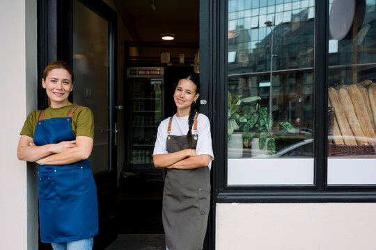 Bakery employees smiling confidently at door in aprons