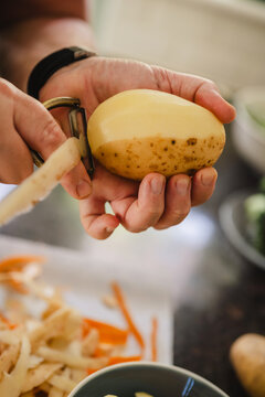 Hand peeling potato in kitchen for healthy home cooking