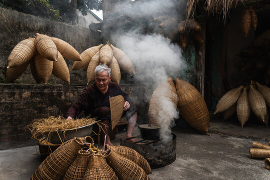 Artisan crafting bamboo fish traps by hand outdoors in Hanoi Vietnam