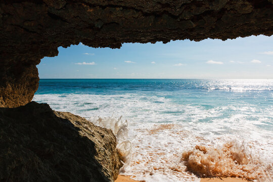 Waves hitting rocks at Dreamland Beach New Kuta Bali under a natural cave