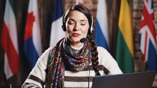 Woman wearing headphones working on laptop in front of multiple international flags