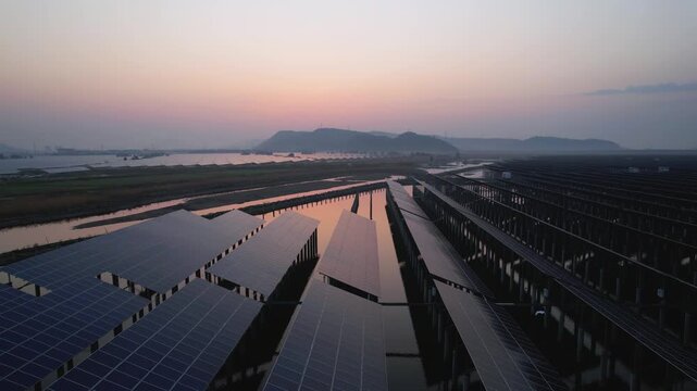 Aerial view of floating photovoltaic power station arrays at dusk with reflections on water surface