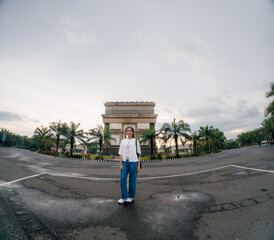 A cheerful Asian woman traveling alone. She looks cheerful on the side of a deserted highway without any vehicles.