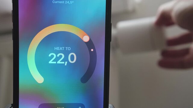 Male hand increasing thermostat temperature with data shown in mobile application.