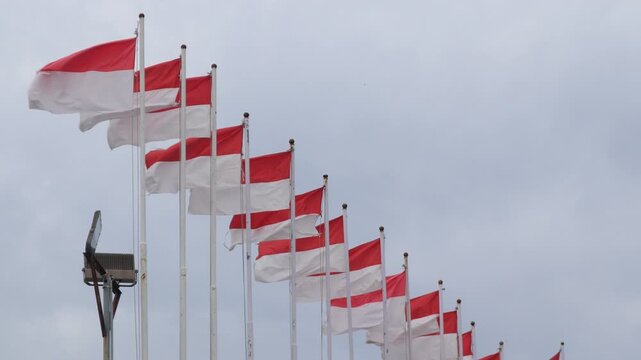 Video The Indonesian flag, Red and White, flies on a pole against a blue sky background.