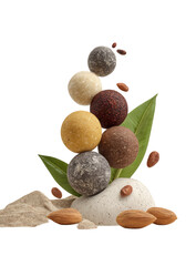 Stacked colorful energy balls on rock, surrounded by almonds, leaves, cloth