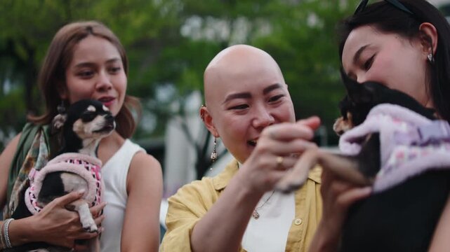 Happy asian women friends playing with chihuahua dogs
