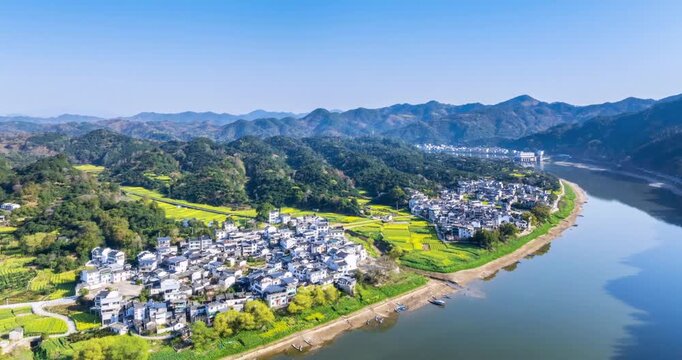 Aerial time-lapse of Xin'an River and traditional villages in Huangshan, showcasing spring scenery with rapeseed fields, mountains, and tranquil waters, Anhui Province, China