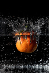 A mandarin falls into a container full of water, raising a large splash