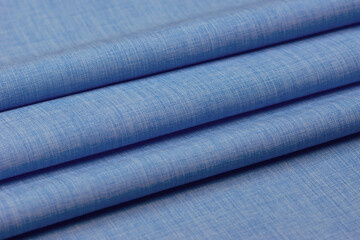 Plain blue fabric folded into folds. Close-up of the sewing fabric.