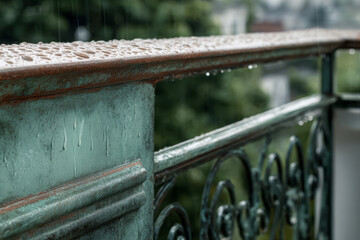 Rainwater collects on a balcony railing in a green setting during a rainy day in the afternoon