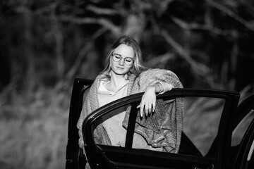 Young woman with long hair leans out of car window, gazing thoughtfully into distance, showcasing a...