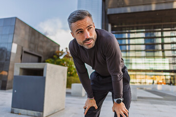 Urban fitness athlete resting after a jog outdoors in city street