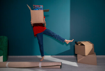 Woman balancing on one leg holding box while unpacking in new home