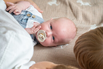 Newborn baby lies on a soft blanket with a visible tear on the cheek while being soothed with a...